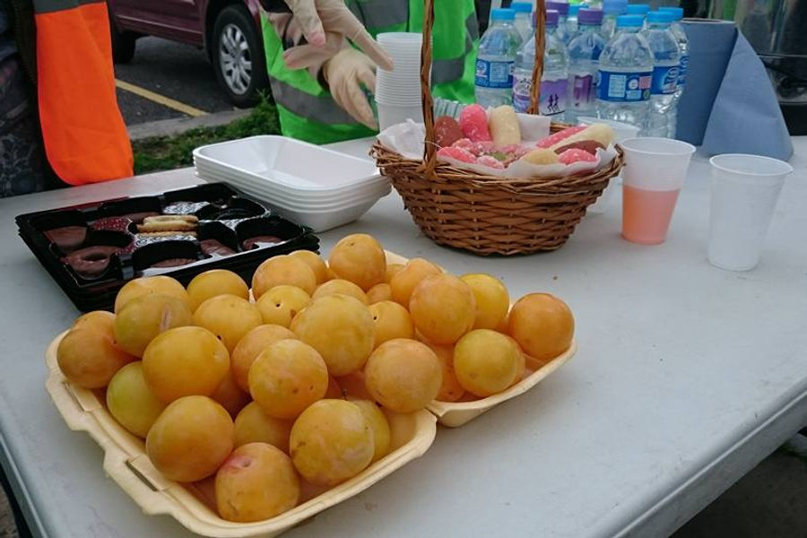 A table laid out with fresh fruit, water bottles and snacks at a community food drive
