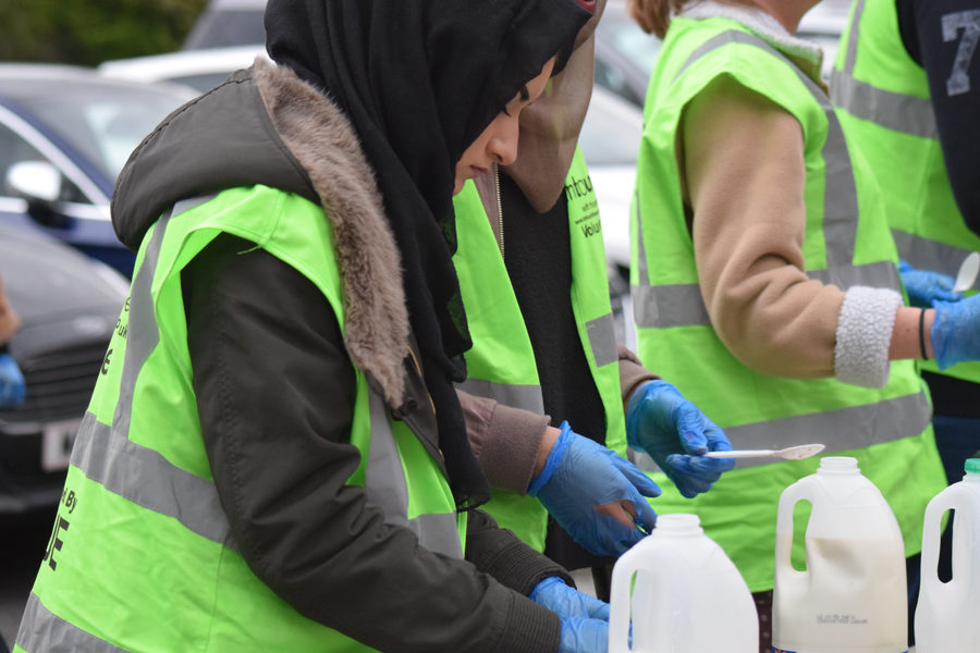 A volunteer in a green InTouch high-visibility vest preparing food at the mobile kitchen